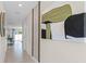 Bright hallway with neutral walls, tan tile floors, and modern artwork, leading to the dining area at 2987 Brie Hammock Bnd, St Cloud, FL 34773