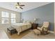 A bright bedroom with wood-look floors, blue accent wall, ceiling fan, chair, and two windows at 3321 Messina Dr, Lake Mary, FL 32746