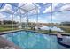 Screened-in pool with a brick-lined edge offers clear blue waters and scenic lake views at 351 Ocean Course Ave, Davenport, FL 33896