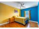 Bright bedroom with blue and yellow accent wall, wood floors, and ceiling fan at 352 Radisson Pl, Oviedo, FL 32765