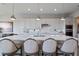 A kitchen island features pendant lighting, white cabinets and countertops and barstool seating at 4228 Sunset Preserve Blvd, Orlando, FL 32820