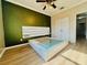 Bright bedroom with wood laminate floors, modern platform bed, stylish ceiling fan, and green accent wall at 561 Telfair Square Ct, Sanford, FL 32771