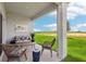 Covered back porch featuring outdoor seating with a view of the green backyard and a bright blue sky at 5929 Cliffbow Loop, Leesburg, FL 34748