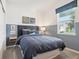 Cozy bedroom featuring half blue-painted walls, a comfy bed, stylish wall art, and natural light from the window at 5929 Cliffbow Loop, Leesburg, FL 34748