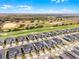 An aerial view shows rows of homes adjacent to a golf course with trees and a water feature, all under a blue sky at 635 Ocean Course Ave # 635, Champions Gate, FL 33896