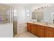 Well-lit bathroom featuring a bathtub, glass-enclosed shower, double sink vanity, and large mirror at 3446 Allegra Cir, St Cloud, FL 34772