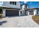 Paver driveway leading to a modern home with multiple garages at 10055 Brocksport Cir, Gotha, FL 34734