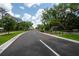 A long driveway leading into the community past an entry gate surrounded by lush trees and landscaping at 10055 Brocksport Cir, Gotha, FL 34734