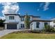 Stunning two-story home featuring a clean white facade, dark gray accents, and a meticulously landscaped front yard at 10055 Brocksport Cir, Gotha, FL 34734