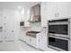 Close up of a kitchen with stainless steel appliances, including a range hood and double oven, with marble backsplash at 10055 Brocksport Cir, Gotha, FL 34734