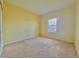 Bright bedroom features neutral carpet, light yellow walls, and a window at 1183 Chervil Dr, Poinciana, FL 34759