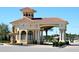 Grand entrance to community featuring beige stucco archway, red tile roof, and decorative water fountain at 1183 Chervil Dr, Poinciana, FL 34759