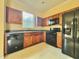 Functional kitchen with wood cabinets, black appliances, and a window over the sink at 1183 Chervil Dr, Poinciana, FL 34759