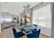 Chic dining area with a modern chandelier, round glass table, comfortable blue chairs and a view into the kitchen at 1204 Pando Loop, Orlando, FL 32824