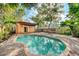 Serene backyard pool surrounded by lush greenery and brick pavers with outdoor lounge space at 122 N Hyer Ave, Orlando, FL 32801