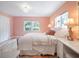 Bright bedroom with pink walls, wood floors, and a plush rug, complemented by a cozy bed and natural light from windows at 1932 Temple Dr, Winter Park, FL 32789