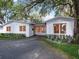 Inviting single-story home with a white exterior, well-manicured landscaping, and a large shade tree at 1932 Temple Dr, Winter Park, FL 32789