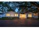 Charming single-story home with lush landscaping and a grand shade tree at twilight at 1932 Temple Dr, Winter Park, FL 32789