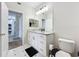 Bright bathroom featuring white cabinetry, a granite countertop, and a white tiled floor with black accents at 580 Water St # F, Kissimmee, FL 34747