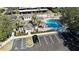 Aerial view of a community pool with palm trees, a clubhouse, parking, and ample lounge space at 583 Brantley Terrace Way # 303, Altamonte Springs, FL 32714