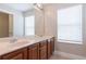 Bathroom featuring double sinks, wood cabinets, tiled flooring and large mirror at 6825 Dolce St, Orlando, FL 32819