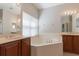 Bathroom featuring a soaking tub, double vanities, and window with blinds for privacy at 6825 Dolce St, Orlando, FL 32819