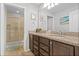 Well-lit bathroom with double vanity, granite countertops, dark wood cabinets, and glass shower at 8920 Rhodes St, Kissimmee, FL 34747