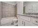 Bright bathroom featuring a tub with tile surround, granite counters and white cabinets at 9157 Harris Hawk Dr, Leesburg, FL 34788