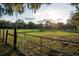 Scenic view of the property featuring a rustic fence, lush field, and sunlit horizon at 9919 Hickory Hollow Rd, Leesburg, FL 34788