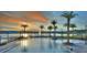 Community swimming pool with palm trees and lounge area during a vibrant sunset at 113 Azure Mist Way, Daytona Beach, FL 32124