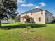 Expansive backyard with a covered patio, lush green lawn, and solar panels on the home's roof at 1144 Legg Dr, Apopka, FL 32712