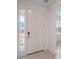 Bright entry showcasing a white front door with glass sidelight and neutral tile flooring at 1260 Tupelo Trl, Haines City, FL 33844