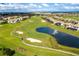 Scenic aerial view of the golf course community with lush green fairways, a tranquil pond, and beautiful homes at 1494 Moon Valley Dr, Davenport, FL 33896