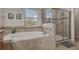 Bright bathroom features a soaking tub beneath a window and a glass-enclosed shower at 1494 Moon Valley Dr, Davenport, FL 33896