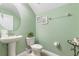 Stylish powder room with green walls, pedestal sink, round mirror, and decorative wall art at 1494 Moon Valley Dr, Davenport, FL 33896