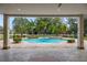 View from the covered patio showcasing a pool, spa, and lush backyard with palm trees and a white fence at 1501 Lake Markham Rd, Sanford, FL 32771