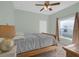 Bedroom with light green walls, ceiling fan, wooden bed frame, and large window at 1843 Van Allen Loop, Auburndale, FL 33823