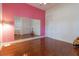 Bedroom with hardwood floors, pink accent wall, and a large mirror at 1910 Lake Roberts Landing Dr, Winter Garden, FL 34787