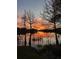 Picturesque lakeside home with a vibrant sunset view, trees and calm water reflecting the orange sky at 200 Maitland Ave # 96, Altamonte Springs, FL 32701