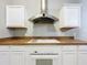 Close up of kitchen appliances featuring white cabinets, an oven, cooktop and vent hood at 250 Youth Camp Rd, Groveland, FL 34736