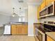 Open kitchen with stainless steel dishwasher, light wood cabinetry, and view of adjoining living area at 411 Old Farm Ln, Winter Springs, FL 32708