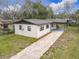 An elevated view of a well-maintained single-story residence featuring a charming white brick exterior, a paved driveway at 425 Walnut St, Daytona Beach, FL 32114