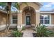 Inviting front entrance features an arched doorway, decorative door, and lush plants at 5019 Log Wagon Rd, Ocoee, FL 34761
