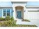 Welcoming home entrance with a charming blue door, lush landscaping, and modern exterior lighting at 5342 Maddie Dr, Haines City, FL 33844