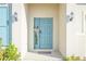 Beautiful blue front door entrance with decorative wreath, sidelight, and stylish outdoor lighting at 5342 Maddie Dr, Haines City, FL 33844
