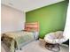 Small bedroom with green accent wall, a wooden bed frame, and cozy chair at 574 Lady Grace Pl, Deland, FL 32724