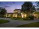 Elegant twilight view of this luxury home with landscape lighting, circular driveway, and lush, manicured grounds at 6126 Kirkstone Ln, Windermere, FL 34786