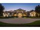 Elegant home featuring manicured landscaping, a circular driveway, and a beautiful stone and stucco facade at twilight at 6126 Kirkstone Ln, Windermere, FL 34786
