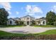 Beautifully landscaped front yard view of a stately home with a circular driveway and manicured garden beds at 6126 Kirkstone Ln, Windermere, FL 34786