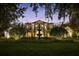 Beautiful two-story home with exterior lighting, showcasing the lush landscaping and architectural details at twilight at 6126 Kirkstone Ln, Windermere, FL 34786